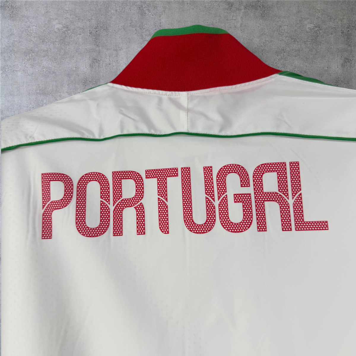 Casaco vintage Portugal 2010/11 da A minha loja, branco com gola vermelha e verde e inscrição Portugal nas costas.
