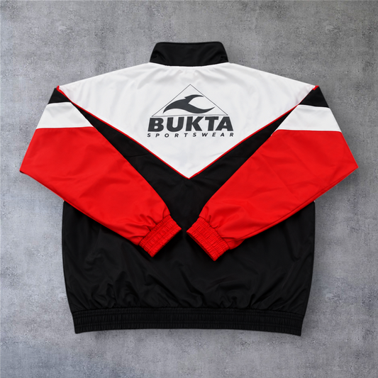 Casaco vintage A minha loja Sevilla 1992/93, design desportivo em preto, branco e vermelho com logótipo Bukta nas costas.