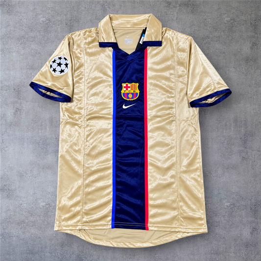 Camisola de futebol A minha loja do Barcelona 2000/01, dourada com risca central azul e emblema da Champions League.