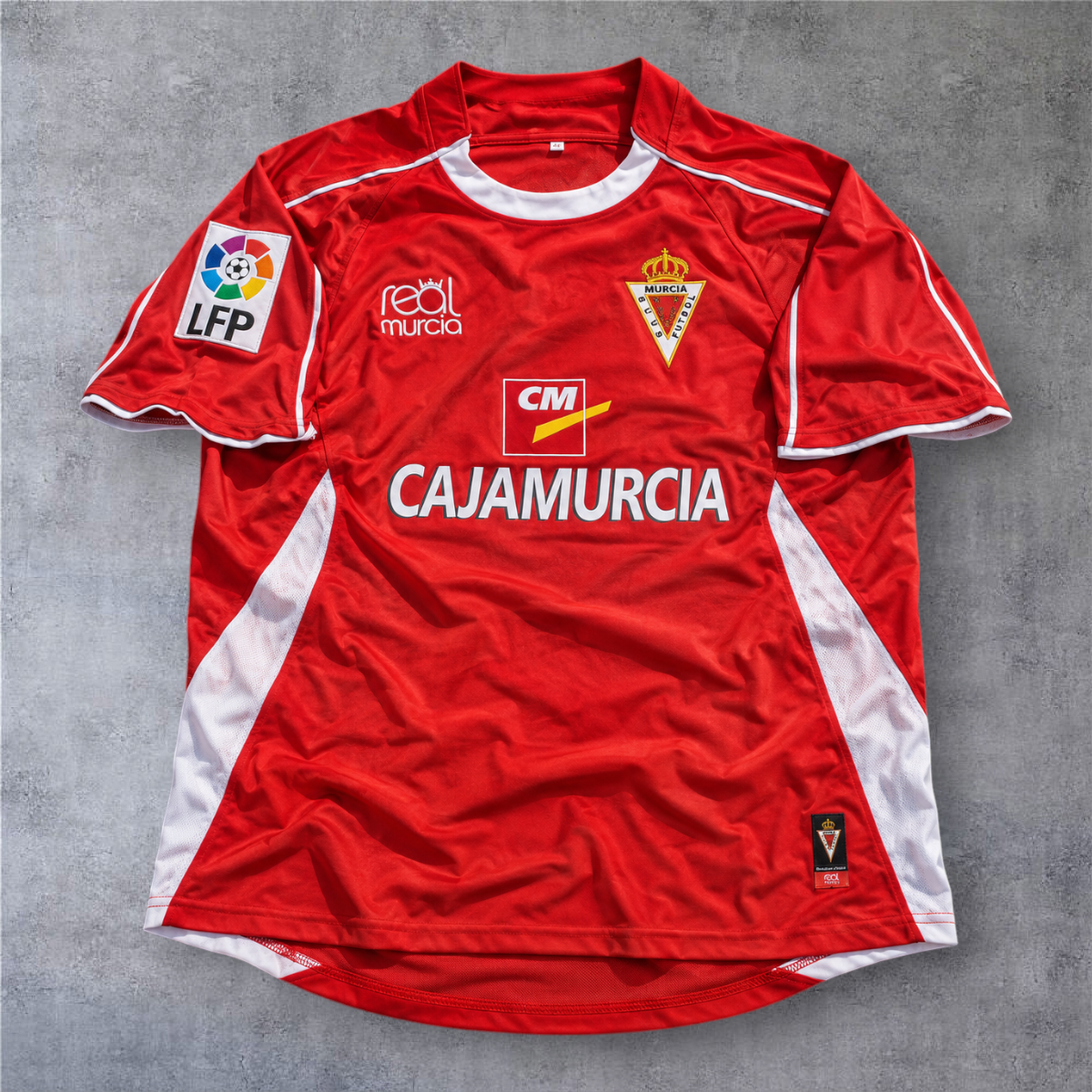 Camisola de futebol A minha loja do Real Murcia 2006/07, vermelha com detalhes brancos e emblema oficial da LFP.