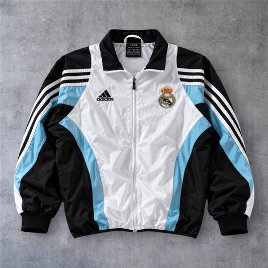 Casaco vintage Real Madrid 2003/04 da A minha loja, com fecho frontal, detalhes em branco, preto e azul claro.