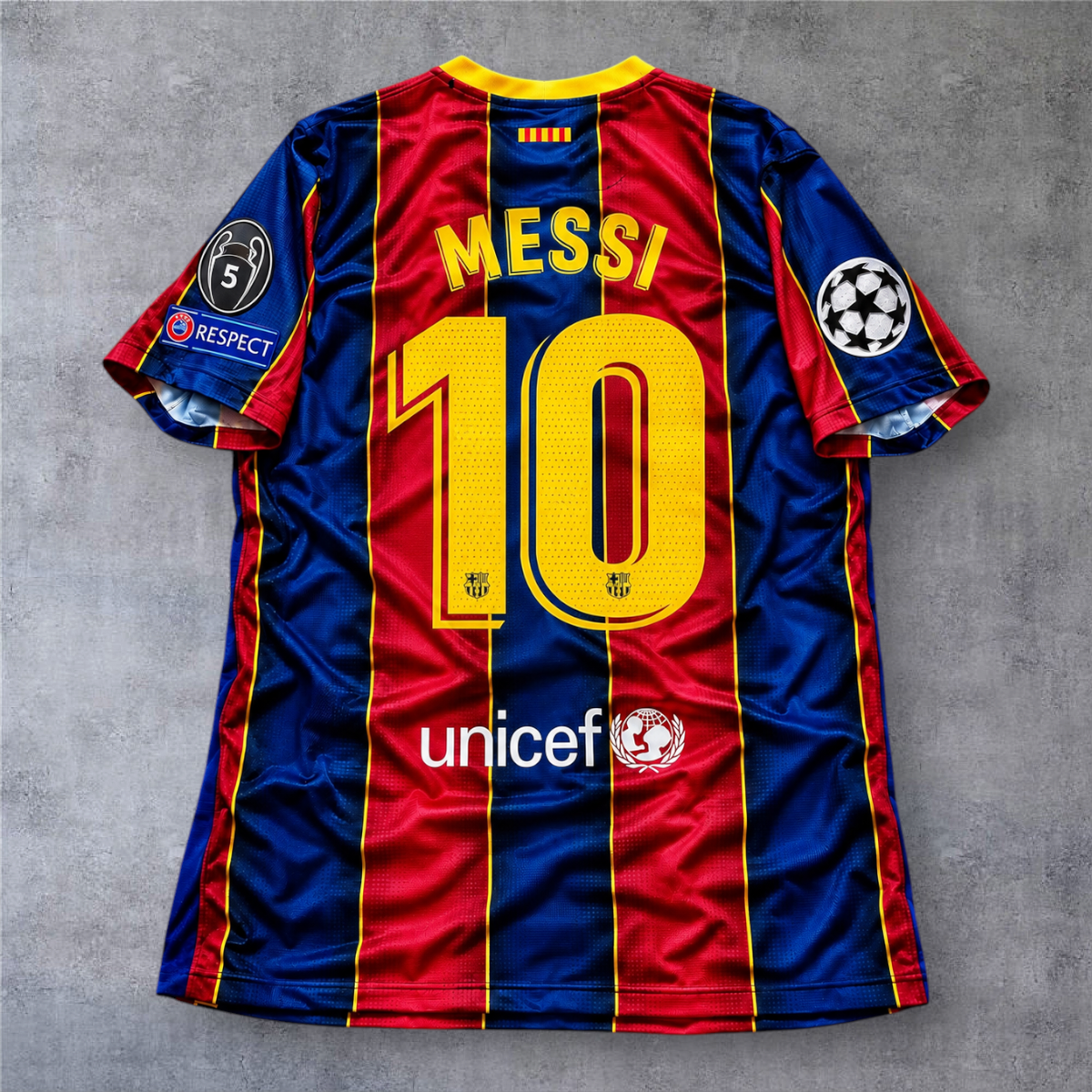 Camisola oficial A minha loja do Barcelona 2020/21 de Messi 10, com emblemas da Champions League e detalhes em azul e vermelho.
