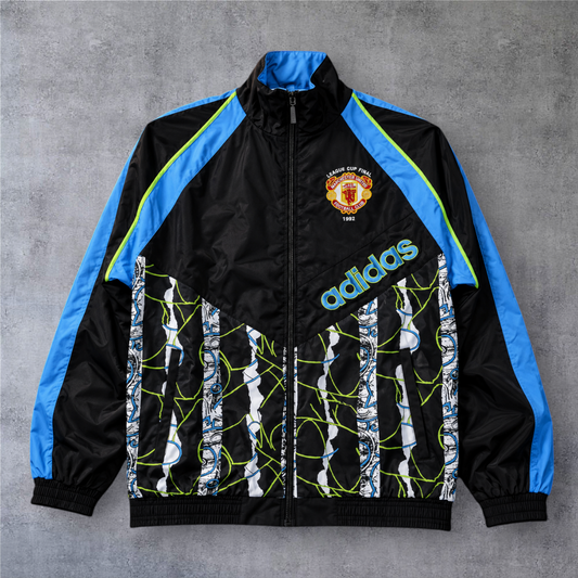 Casaco vintage A minha loja Manchester United 1990/91, preto e azul com fecho frontal e detalhes gráficos retro.