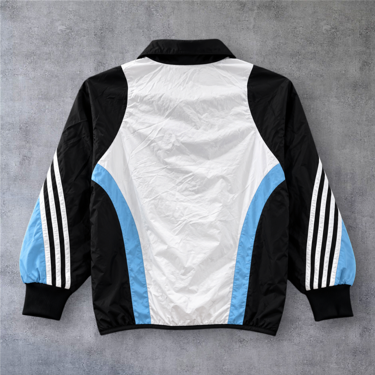 Casaco vintage Real Madrid 2003/04 da A minha loja, com design tricolor em branco, preto e azul e fecho frontal.