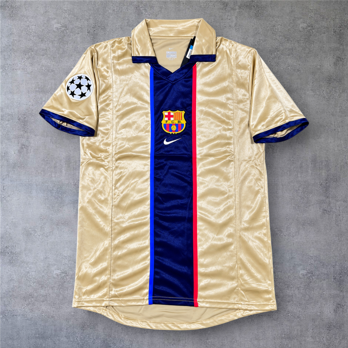 Camisola A minha loja do Barcelona 2001/02 fora, dourada com risca central azul e emblema da Champions League.