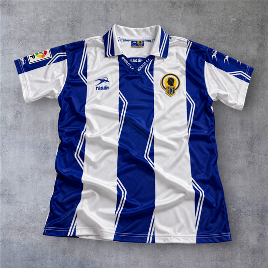 Camisola de futebol A minha loja do Hercules CF 1997/98, listada em azul e branco com gola polo e emblema do clube.