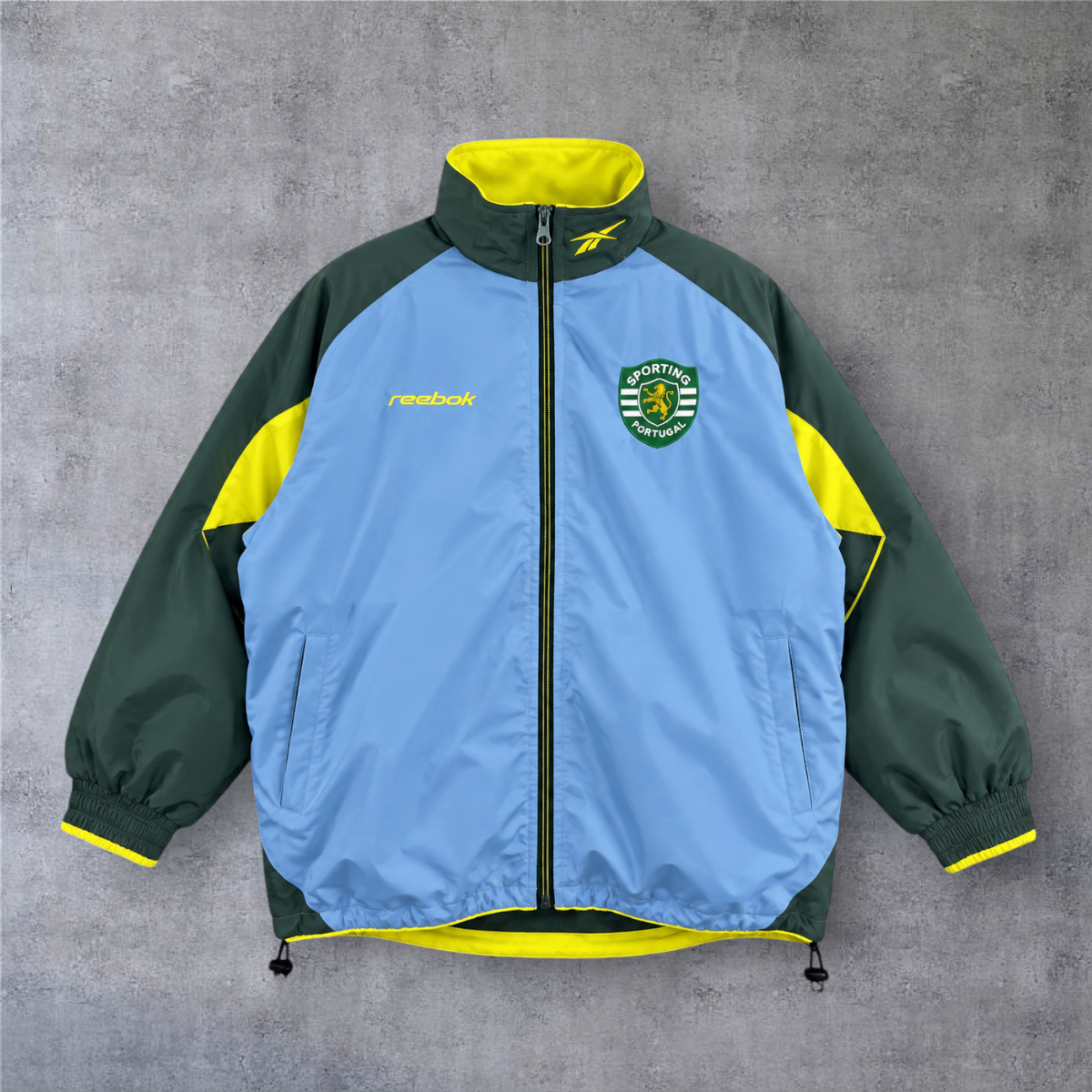 Casaco vintage Sporting 2003 A minha loja, azul e verde com detalhes em amarelo, fecho completo e emblema do clube.