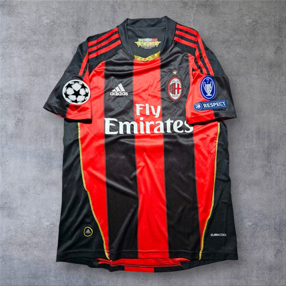 Camisola de futebol A minha loja AC Milan 2010/2011, modelo principal com riscas pretas e vermelhas e detalhes dourados