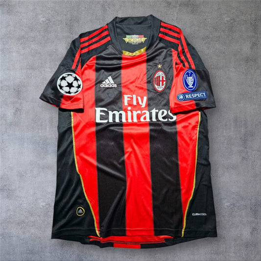 Camisola de futebol A minha loja AC Milan 2010/2011, modelo principal com riscas pretas e vermelhas e detalhes dourados