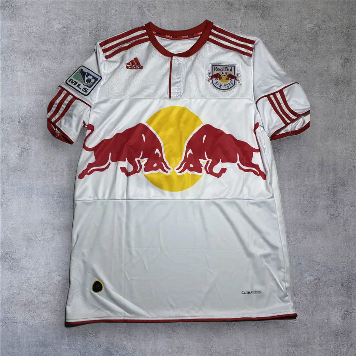A minha loja camisola de futebol branca e vermelha NY Red Bulls 2011/12 com o icónico touro vermelho e um sol amarelo. Tecido leve.