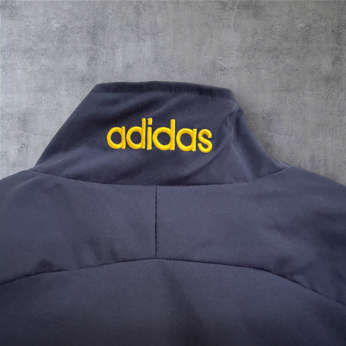 Detalhe da gola do casaco vintage da Espanha 1996 da A minha loja com logótipo adidas bordado em amarelo